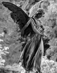 A black and white photo of a weathered statue of an angel