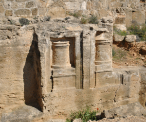 Close-up of two ancient, decorative columns carved directly into a weathered sandstone rock face.