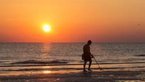 man walking at the beach with metal detector