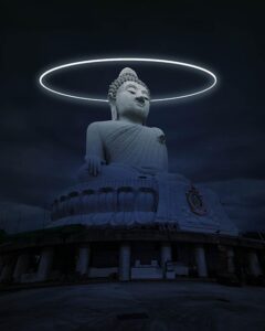 A huge, stone statue of Buddha sits under a glowing, circular halo against a dark, cloudy sky