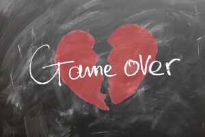 A red broken heart is drawn on a blackboard with the words "Game Over" written across it in white chalk