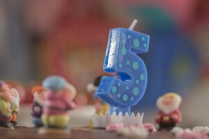 A blue birthday candle shaped like the number '5' with light blue polka dots