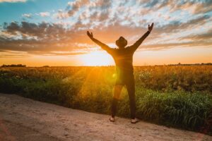 man with stretched hands looking at sunrise