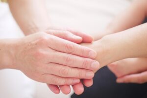 a close-up shot of two hands, one gently holding the wrist/forearm of another