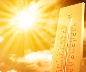 A thermometer showing a high temperature against a bright, blazing sun.