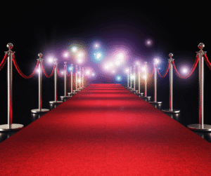 Red carpet framed by stanchions leads toward glowing flashing lights.
