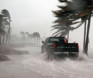 A pickup truck drives through flooded streets during severe hurricane winds.
