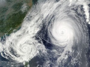 An aerial view of two large, swirling hurricane systems over an ocean