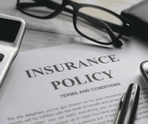 An insurance policy document sits beside eyeglasses and a calculator.