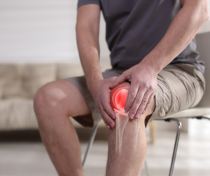 Person holding knee with red highlight indicating joint pain