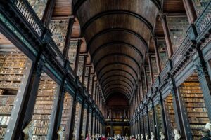 the grand, elongated main chamber of a historic library, characterized by towering dark wooden bookshelves filled with books on multiple levels