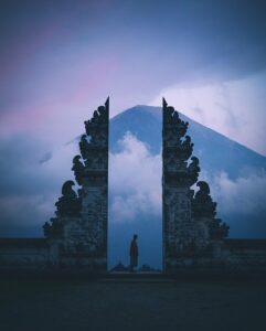 a traditional Balinese temple gate, framing a majestic, cloud-shrouded mountain in the background
