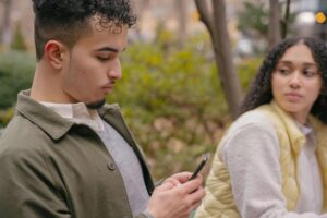 lady looking jealously at boyfriend while texting on cellphone