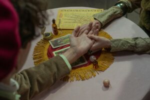 A tarot card reading setup with candles, crystals, and mystical elements arranged on a dimly lit table.