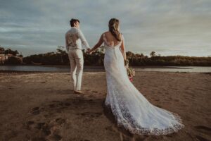 bride and groom walking on sandy coastline