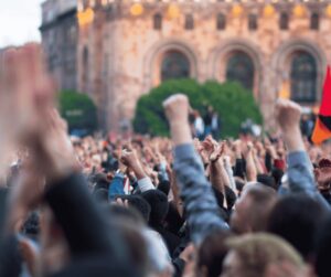 A crowd of people raises their hands and fists during a rally.