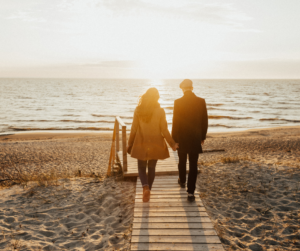 couple walking along a path facing the sunset
