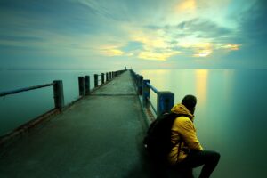 man thinking sitting by the beach sunset