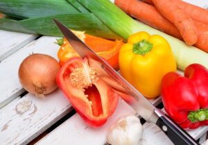Various colorful vegetables and a knife on a rustic wooden surface