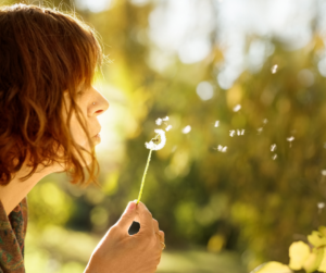 woman blowing dandelion