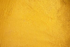 a close-up, textured shot of a surface that appears to be painted or covered in a bright, vibrant gold